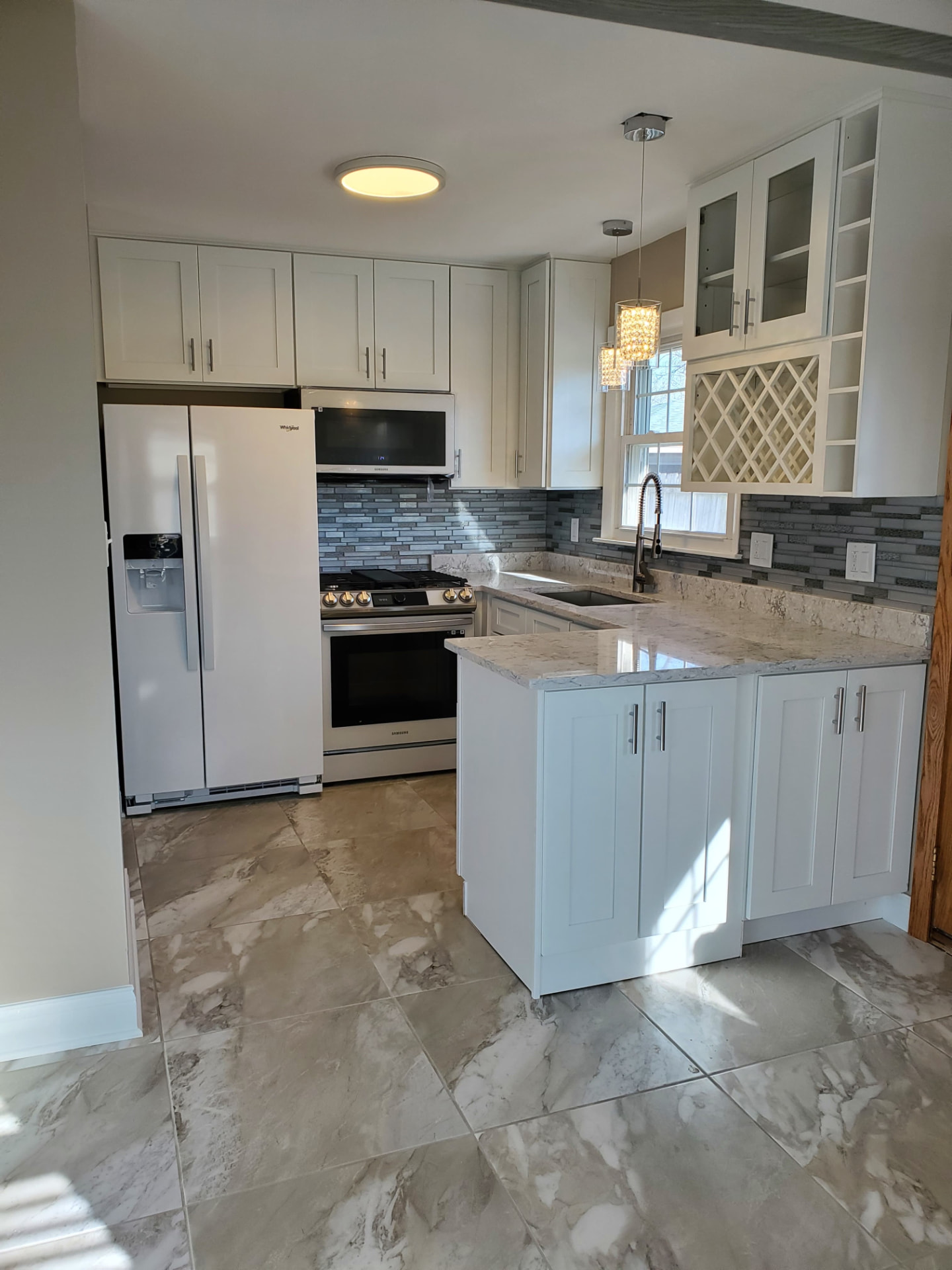 Kitchen with white cabinets, granite countertops, and gray glass tile backsplash